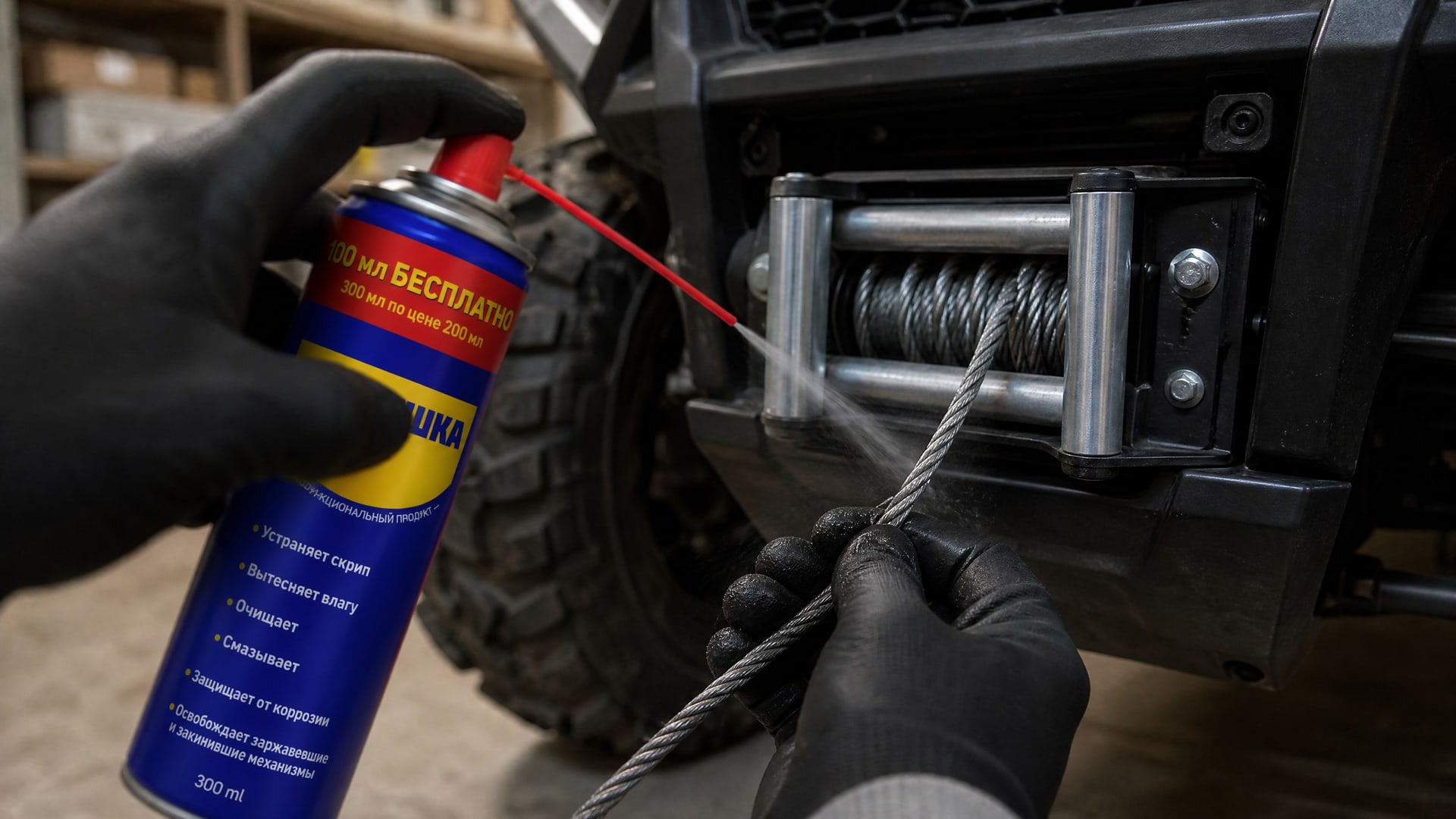 Рука в перчатке наносит универсальную смазку WD40 на трос лебедки. Рука в перчатке наносит универсальную смазку WD40 на трос лебедки.