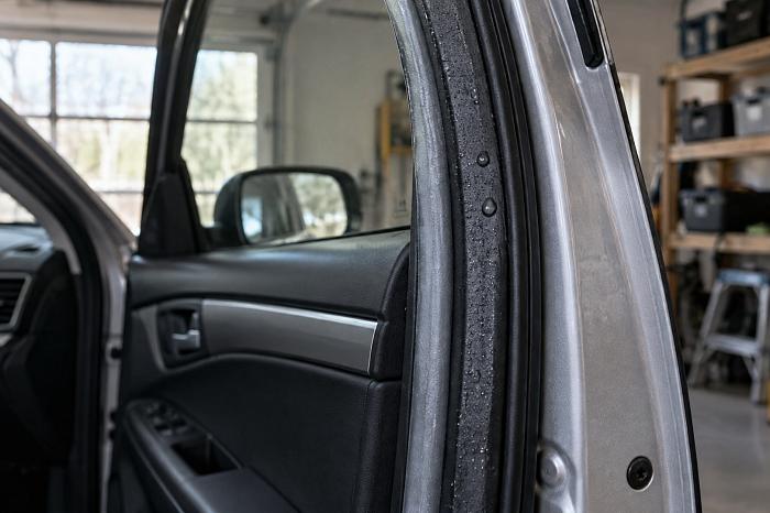 Открытая дверь автомобиля, резиновый уплотнитель с каплями воды в домашнем гараже.